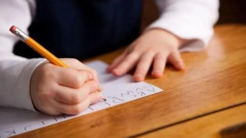 A closeup of a child writing with a pencil