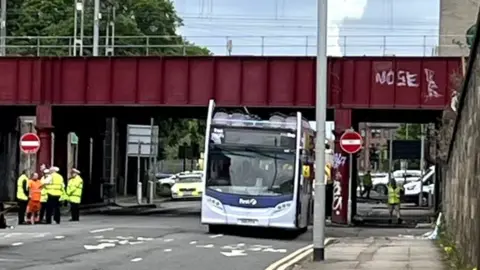 A bus under a bridge with the roof torn off
