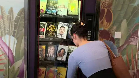 Woman swapping book from vending maching