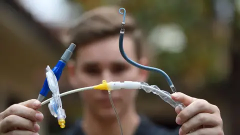 A teenage boy holding a right-sided Impella heart pump towards the camera