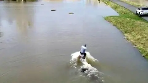 Man wakeboarding through Berkshire flood water