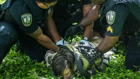 Police officers detain a demonstrator