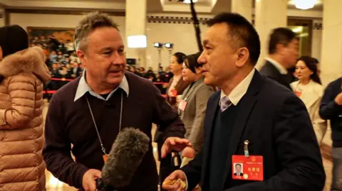 BBC correspondent Stephen McDonell holds microphone in front of a delegate at China's National People’s Congress