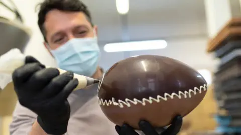 A chocolate maker works on an Easter egg