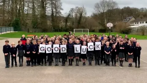 School children holding a 'good luck' sign in the school playground