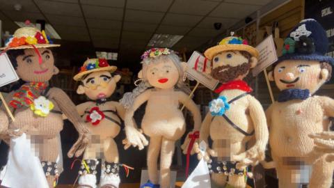 Five naked knitted figures in a cafe window 