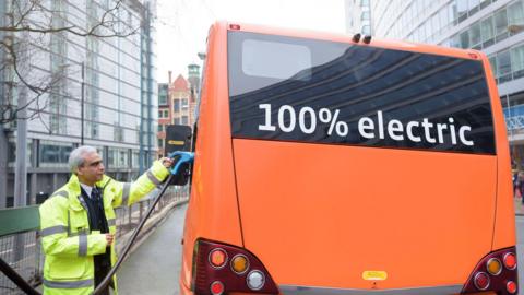 Bus driver charging electric bus at charging station