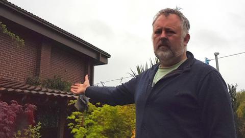 A man in his garden points towards where the new McDonald's would be