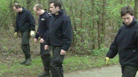 Police pictured searching woods after the discovery of the baby 
