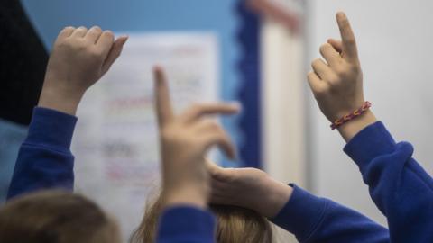 Students with hands up in classroom