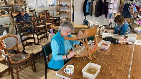 A woman in the Woodhouse Centre repairing a chair