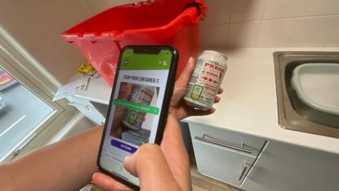 someone depositing their can using a smartphone