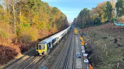 Train passing repair work after landslip near Woking