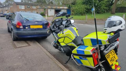 A police bike parked next to a car on a residential estate