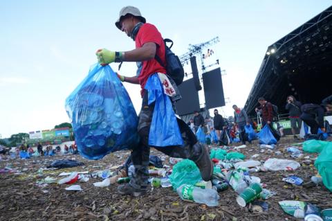 A man with a bin bag clears litter at Glastonbury