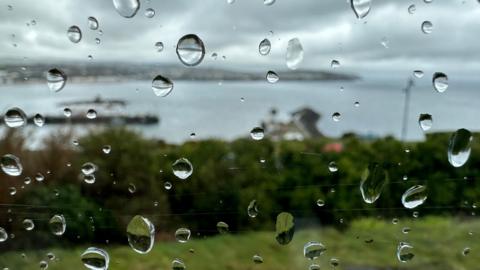 Rain on a window overlooking a headland