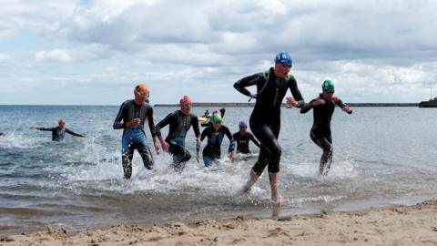Competitors exit the water during the mixed relay event, on day two of the 2023 World Triathlon Series event at Roker Beach, Sunderland