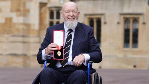 Michael Eavis with the medal awarded to him for his knighthood
