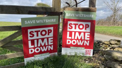 Two posters against a solar farm
