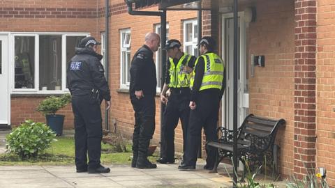 Four police officers standing outside a property