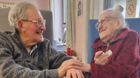 Elderly couple holding hands in hospital