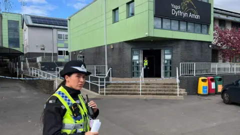 a policewoman standing outside the school after the incident on Monday