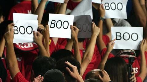 Hong Kong fans hold up signs with the words Boo on them