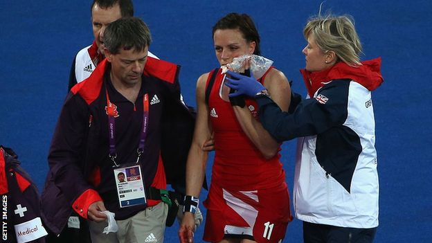 Kate Richardson-Walsh ices her jaw as she is led off the pitch after breaking it