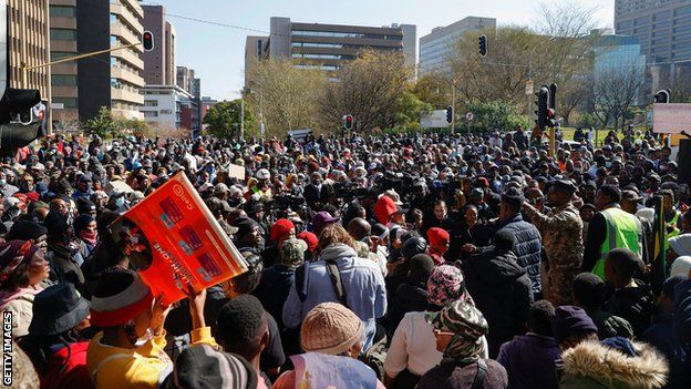 Soweto township residents sing and chant slogans while holding placards as they march in the Johannesburg Central Business District to deliver a petition at the Mayors office on June 21, 2022, for what they say is a general lack of service delivery and electricity in their community.