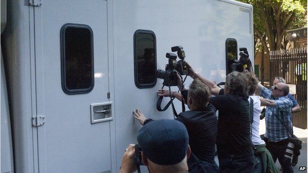 Press photographers trying to get pictures through the window of a prison van
