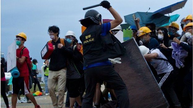 A policeman clashes with pro-democracy protesters during an operation to clear an occupied road near the government headquarters in the Admiralty district of Hong Kong early on 1 December 2014