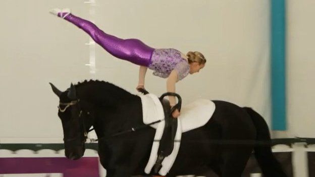 woman performing a gymnastic move on a horse