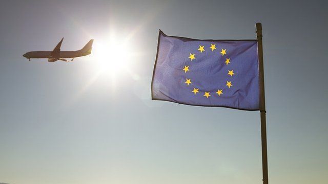 a plane flying past an EU flag