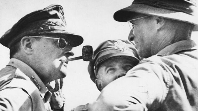Генерал Макартур (слева) со своей знаменитой трубкой во рту говорит с помощниками