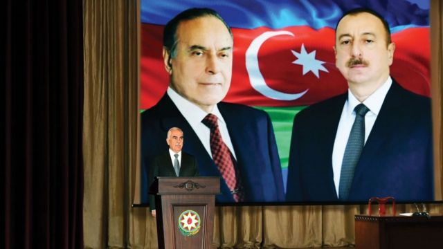 Талыбов на фоне портретов Гейдара и Ильхама Алиевых