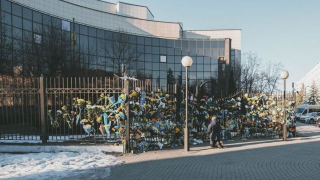 Люди принесли цветы к посольству Украины в Минске. Один из пришедших стоит на коленях. Минск, 27 февраля 2022