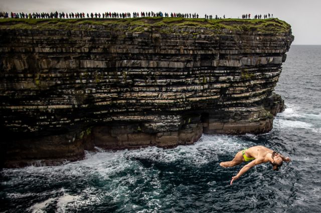 Каталин Преда из Румынии прыгает с 27-метровой платформы на Мировой серии Red Bull Cliff Diving, Даунпатрик-Хед, Ирландия в сентябре 2021 года.