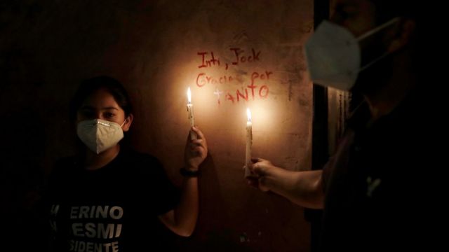 Women hold candles next to the names of two people who were killed in clashes during protests following the ouster of President Martin Vizcarra, in Lima, Peru November 15, 2020. The writing reads "Inti, Jack, thank you for so much"