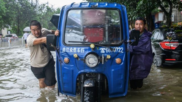 Жители города Шаогуань в провинции Гуандун толкают свою машину по затопленной улице