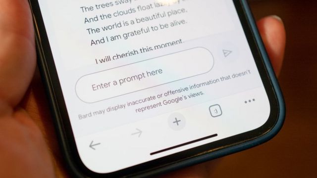 Person's hand holding an iPhone displaying Google's Bard AI chatbot with prompt entry field