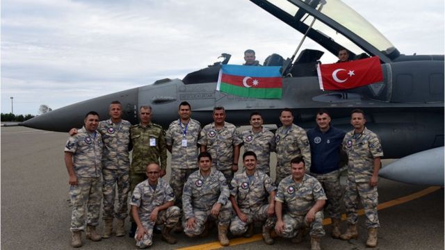 Азербайджанские и турецкие военные на фоне истребителя и флагов двух государств