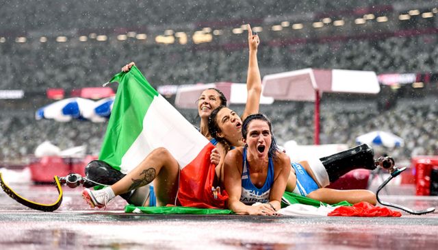 Итальянка Амбра Сабатини празднует завоевание золота и установление мирового рекорда в беге на 100 метров среди женщин вместе с соотечественницами Мартиной Кайрони и Моникой Контрафатто, занявшими второе и третье места на Паралимпийских играх в Токио.