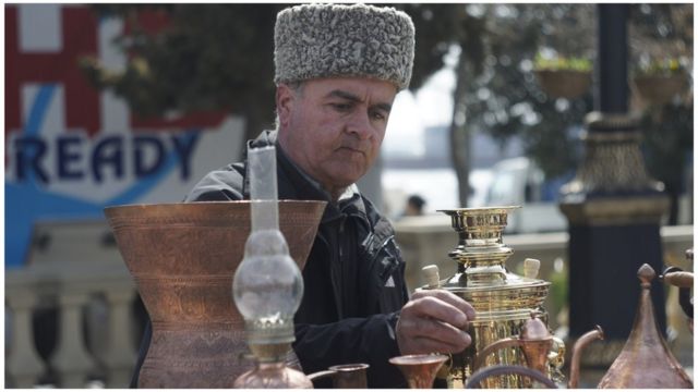 Продавец антиквариата в национальной каракулевой шапке в центре Баку.