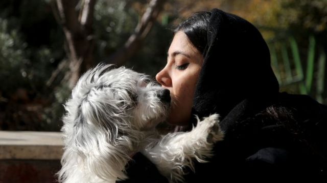 Молодая иранка целует свою собаку