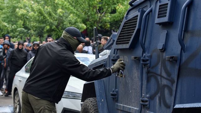 Демонстрант в Звечане с закрытым лицом рисует на бронеавтомобиле Z 29 мая 2023 года