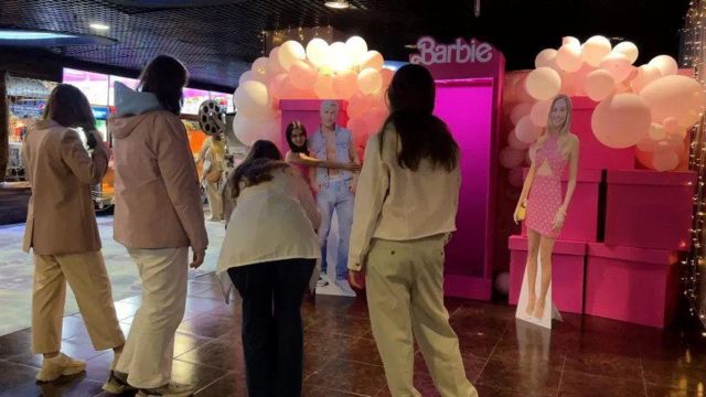 Посетители российского кинотеатра около картонных героев фильма "Барби"