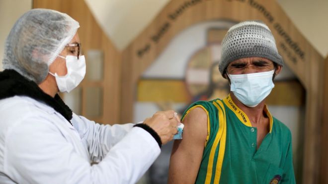 Женщина вакцинирует мужчину в Бразилии