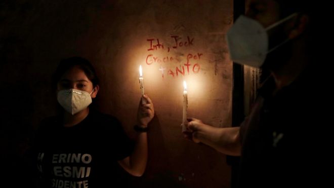 Women hold candles next to the names of two people who were killed in clashes during protests following the ouster of President Martin Vizcarra, in Lima, Peru November 15, 2020. The writing reads "Inti, Jock, thank you for so much"