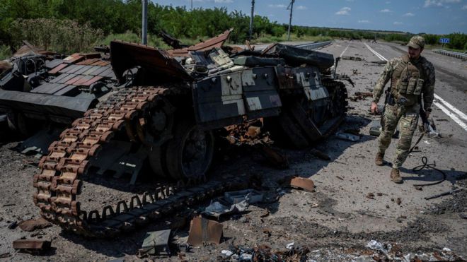 Украинский военный рядом с подбитым танком