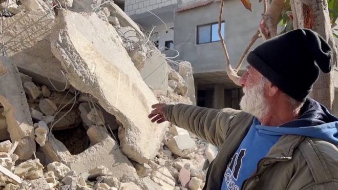Сириец смотрит на развалины своего дома